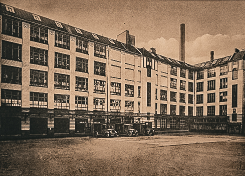 Eine Außenansicht der ehemaligen Wurstfabrik, aufgenommen 1913. Die Fabrik ist in Betrieb und man kann die Lieferwagen vor dem Gebäude sehen.